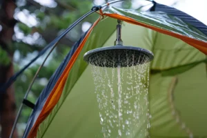 Retkisuihku roikkuu teltassa, josta virtaa vettä virkistävänä suihkuna camping-olosuhteissa.